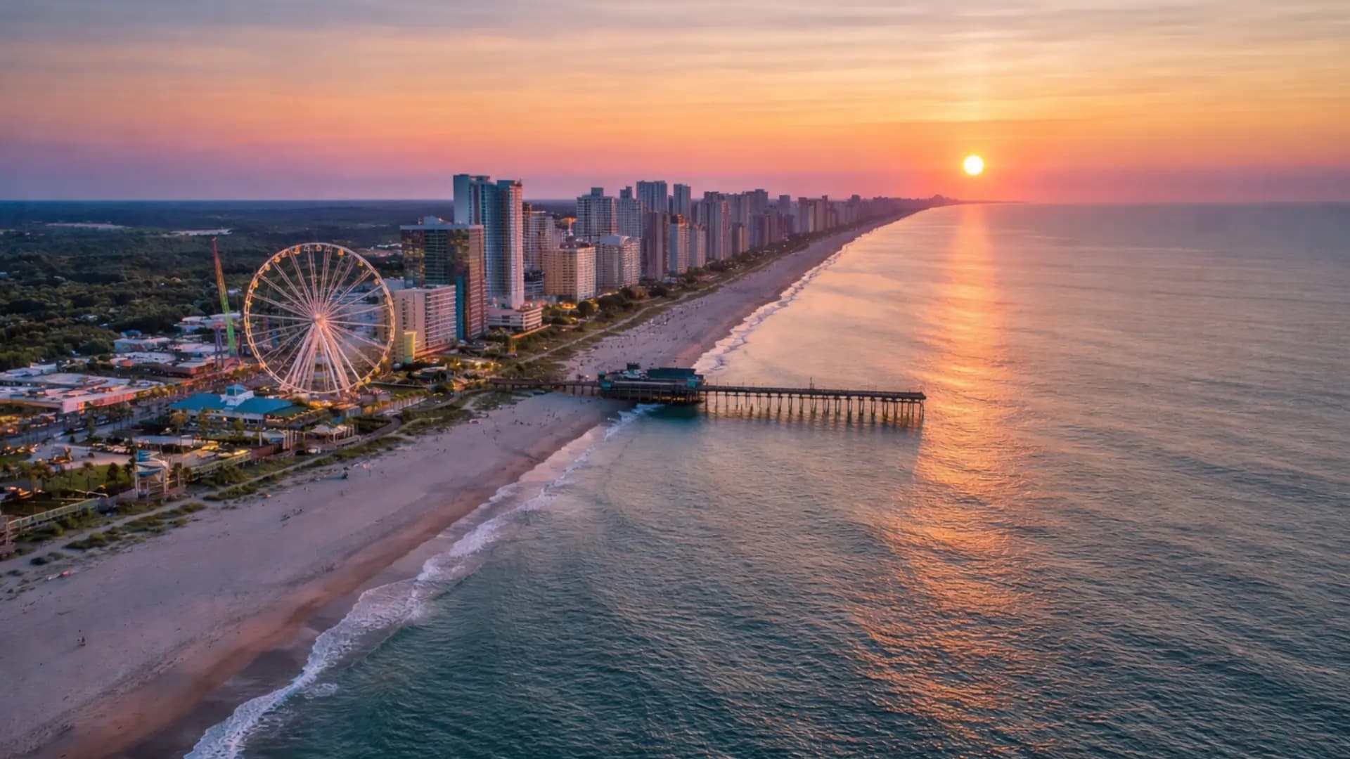 Aerial view of Myrtle Beach, South Carolina at sunset with the SkyWheel, oceanfront pier, and coastline