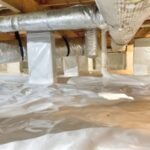 A crawl space under a house that has been covered with a plastic vapor barrier.